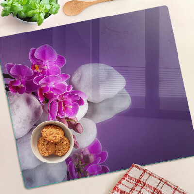 Üveg vágódeszka Orchidea virágok kövek hátterében