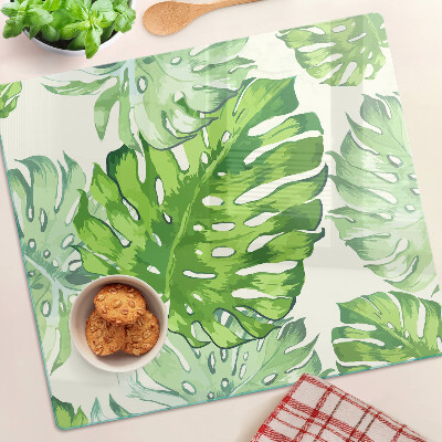 Edzett üveg vágódeszka Monstera levelek világos háttér előtt