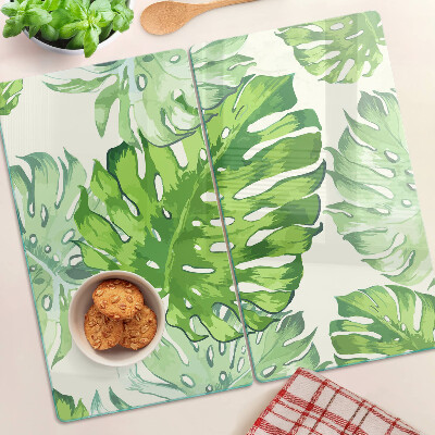 Edzett üveg vágódeszka Monstera levelek világos háttér előtt
