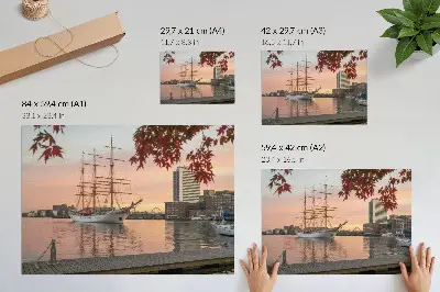 Poszter vitorlás hajó naplementében a város békés panorámájával